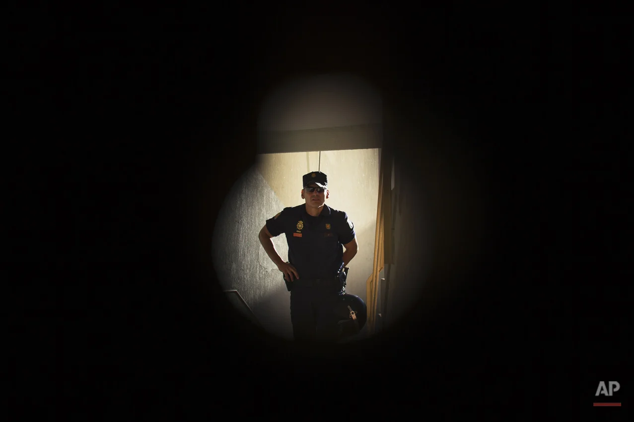 A riot police officer, seen through the keyhole, arrives to evict Juan Jose Munoz Escudero, 29 years old, and his family in Madrid, Spain, Monday, June 16, 2014. Juan Jose Munoz Escudero his wife Tamara de la Cruz Bermudez, 27 years old, and his one year old baby live with a low income coming from selling goods in the street and state benefits of 423 euros ($574). They occupied the apartment and have tried to negotiate to pay a low protected rent to the City Hall Housing and Land Company (EMVS) but the company demanded their eviction. EMVS, a state company with an aim to give housing solutions for people in need, sold 1.860 state apartments to private investors, last year. (AP Photo/Andres Kudacki)