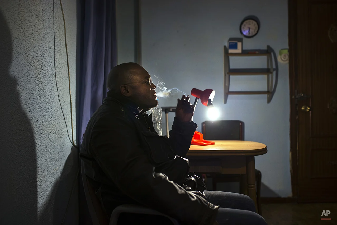 Jorge Filipe Bento, 45 years old, unemployed, from Angola with Spanish nationality, smokes as he waits for the judicial commission and the police to arrive during his eviction in Madrid, Spain, Thursday, Feb. 20, 2014. Bento purchased the euro 165,000 (US$ 225,985) apartment by taking a mortgage with Bankia bank in 2008, but ceased making payments after losing his job as a security guard in 2010. He lost the apartment to the bank and still owes euro 31,541 (US$ 43,200). The eviction was postponed the help of the Victims' Mortgage Platform (PAH). (AP Photo/Andres Kudacki)