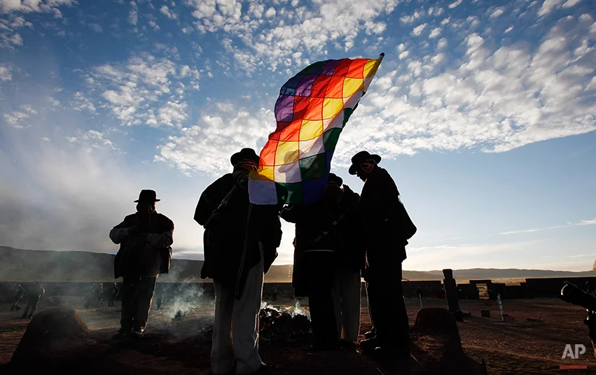 Aymara indigenous men with a Wiphala flag, representing Andean Indians in South America, attend a new years ritual at the ruins of the ancient civilization of Tiwanaku located in the highlands in Tiwanaku, Bolivia, early Saturday, June 21, 2014. Bolivia's Aymara Indians are celebrating the year 5,522 as well as the Southern Hemisphere's winter solstice, which marks the start of a new agricultural cycle. (AP Photo/Juan Karita)