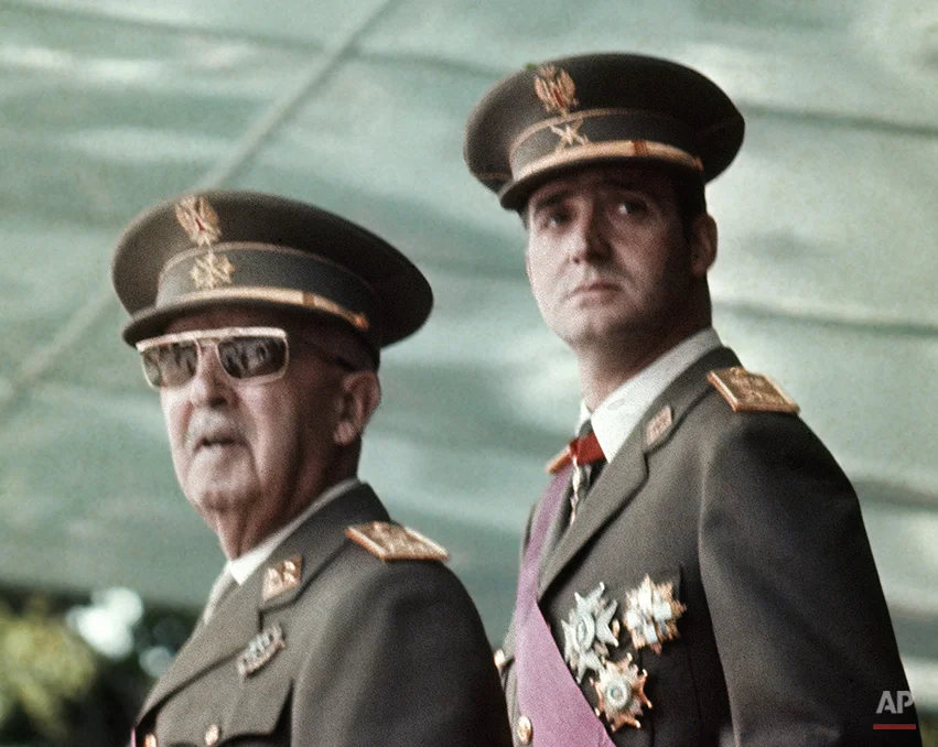 In this May 1973 file photo of Spain's leader Francisco Franco, left, with his future successor as King, Prince Juan Carlos de Borbon, as they watch a military parade in Madrid . Spain’s King Juan Carlos will abdicate and pave the way for his son, Crown Prince Felipe, to take over, Spanish Prime Minister Mariano Rajoy told the country Monday in an announcement broadcast nationwide. He did not say when Juan Carlos would abdicate because the government must now craft a law creating a legal mechanism for the abdication and for 46-year-old Felipe’s assumption of power. King Juan Carlos came to power in 1975, two days after the death of longtime dictator Francisco Franco. He endeared himself to many Spaniards in large part by putting down an attempted military coup in 1981 when he was a young and largely untested head of state. (AP Photo)