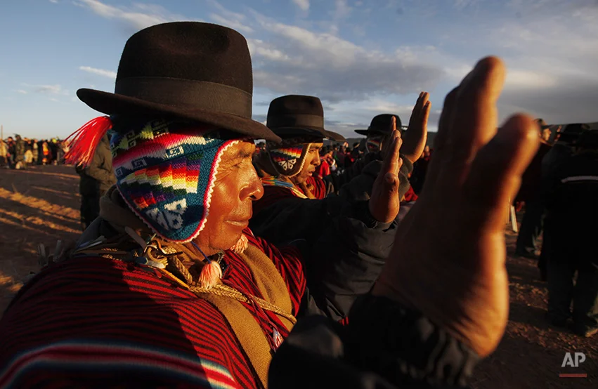 Aymara men hold up their hands to the first rays of sunlight during a new years ritual at the ruins of the ancient civilization of Tiwanaku located in the highlands in Tiwanaku, Bolivia, early Saturday, June 21, 2014. Bolivia's Aymara Indians are celebrating the year 5,522 as well as the Southern Hemisphere's winter solstice, which marks the start of a new agricultural cycle. (AP Photo/Juan Karita)
