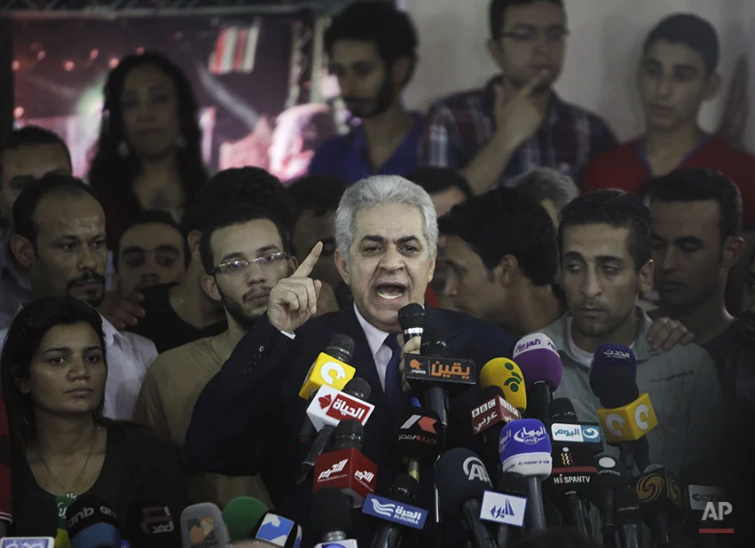 Presidential hopeful Hamdeen Sabahi talks as he is surrounded by his campaign members during a press conference at his campaign headquarters in Cairo, Egypt, Thursday, May 29, 2014. The defeated candidate in Egypt's presidential candidate has accepted defeat by the nation's former military chief, but said turnout figures announced by the government are not credible. With nearly all ballots counted, Egypt's former military chief, retired field marshal Abdel-Fattah el-Sissi, has won a crushing victory over his sole opponent Sabahi in the country's presidential election, his campaign said Thursday. But the results were stained by questions about turnout despite a robust government effort to get out the vote. (AP Photo/Amr Nabil)