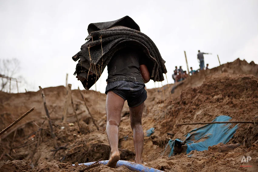 In this Friday, May 2, 2014 photo, a gold miner carries special carpets that are used to filter sand for gold at an illegal mine in La Pampa in the Madre de Dios region of Peru. Illegal mining accounts for about 20 percent of Peru's gold exports, and most miners are poor migrants from the Andean highlands. (AP Photo/Rodrigo Abd)