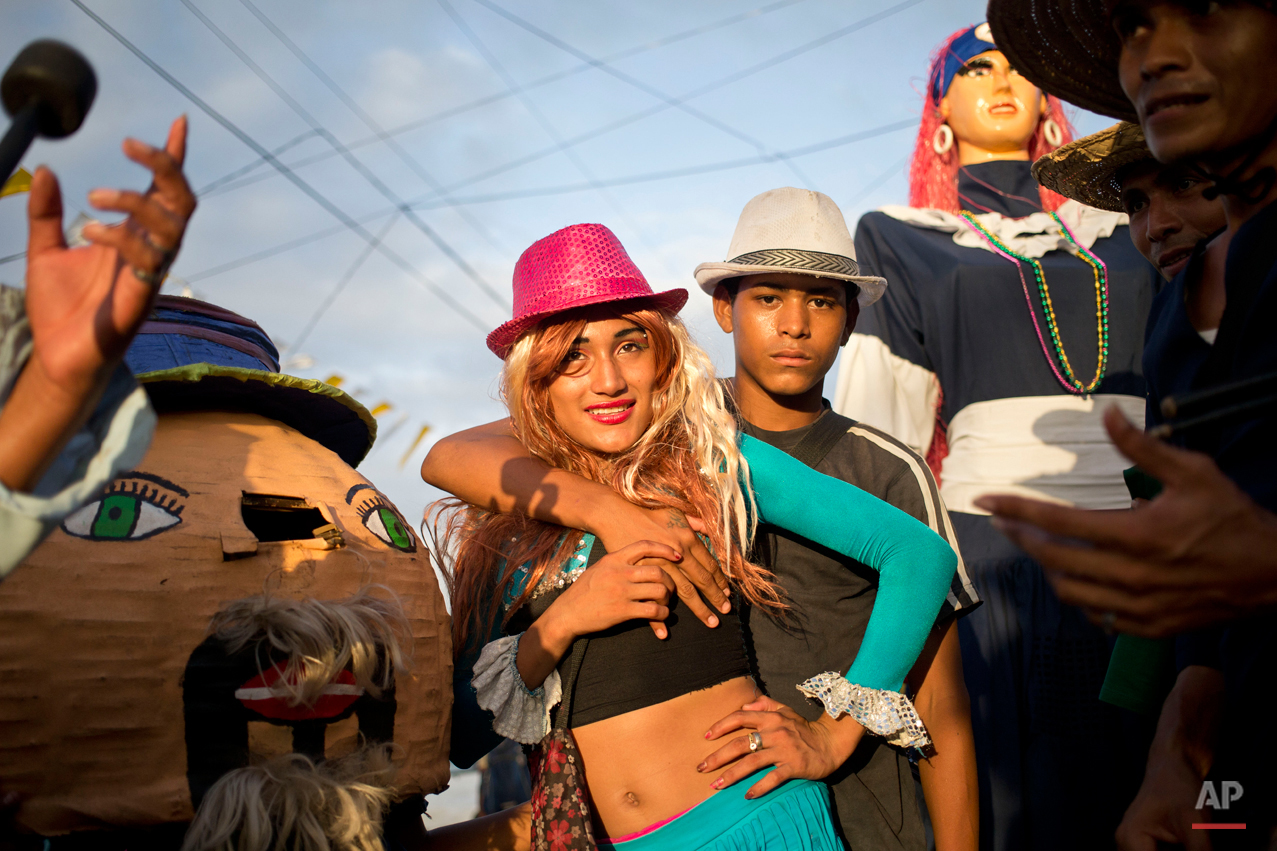  In this Aug. 7, 2015 photo, two men dressed as a couple pose for a photo next to traditional dolls known as a "Gigantona," right, and a "Pepe Cabezon," left, during Managua's patron saint, Santo Domingo de Guzman's celebration, in Managua, Nicaragua