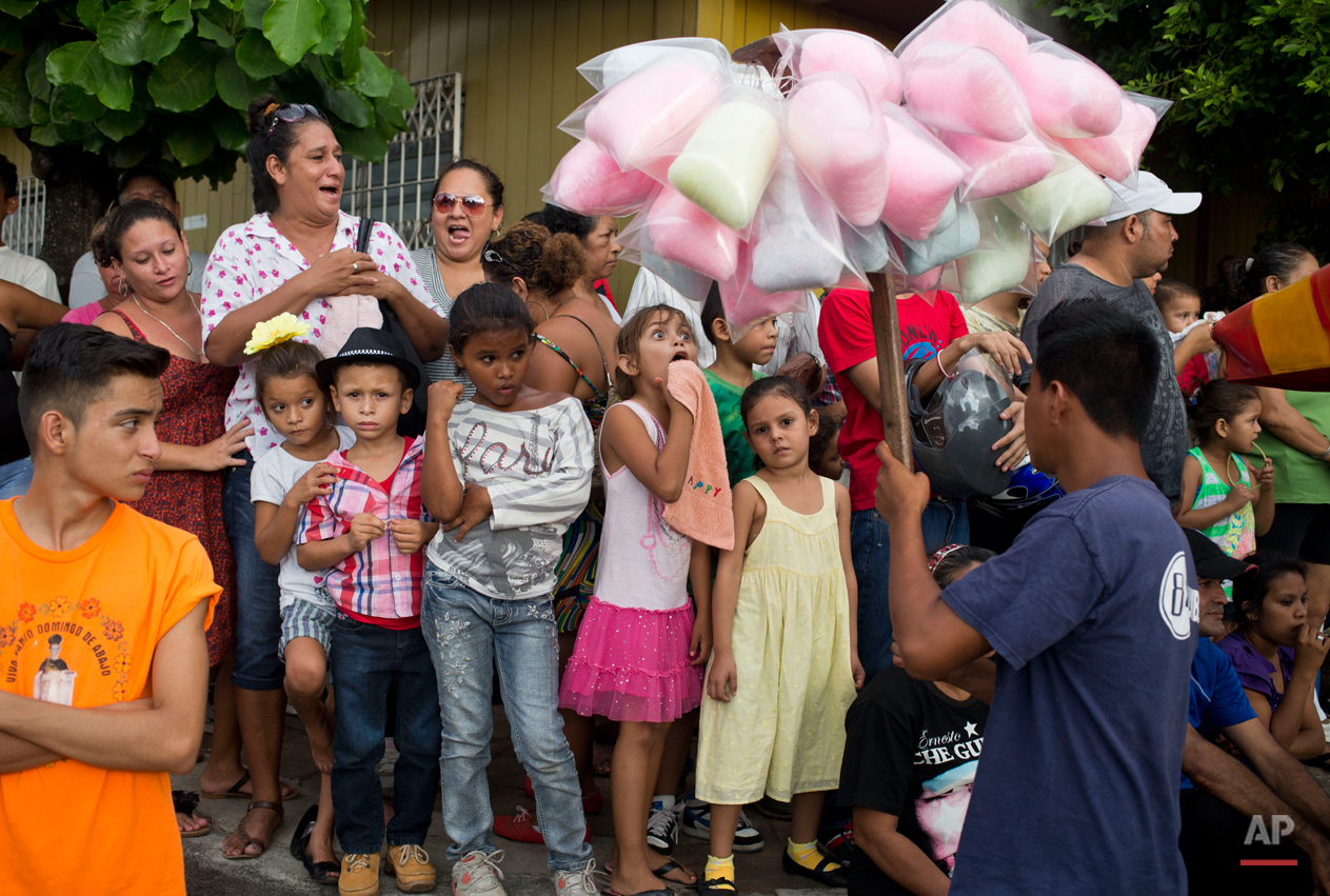  In this Aug. 7, 2015 photo, a girl makes a face as she reacts to cotton candy for sale during Managua's patron saint, Santo Domingo de Guzman's celebration, in Managua, Nicaragua. Outside the Santo Domingo Las Sierritas parish vendors hawk all kinds