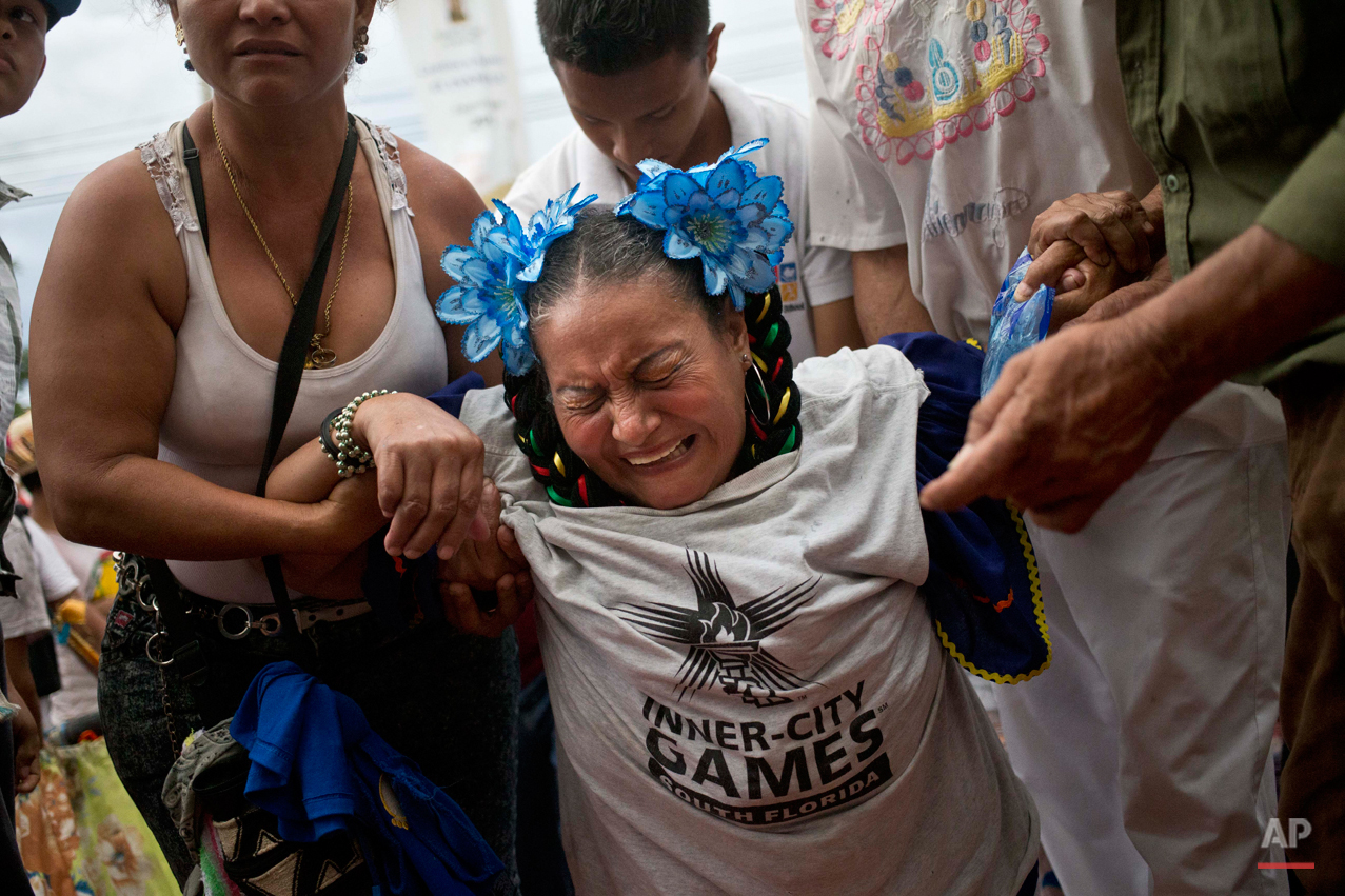  In this Aug. 10, 2015 photo, a ìpromesanteî or devotee, grimaces in pain as she moves towards the Las Sierritas parish church, on her knees, assisted by relatives during Managua's patron saint, Santo Domingo de Guzman's celebration, in Managua, Nica