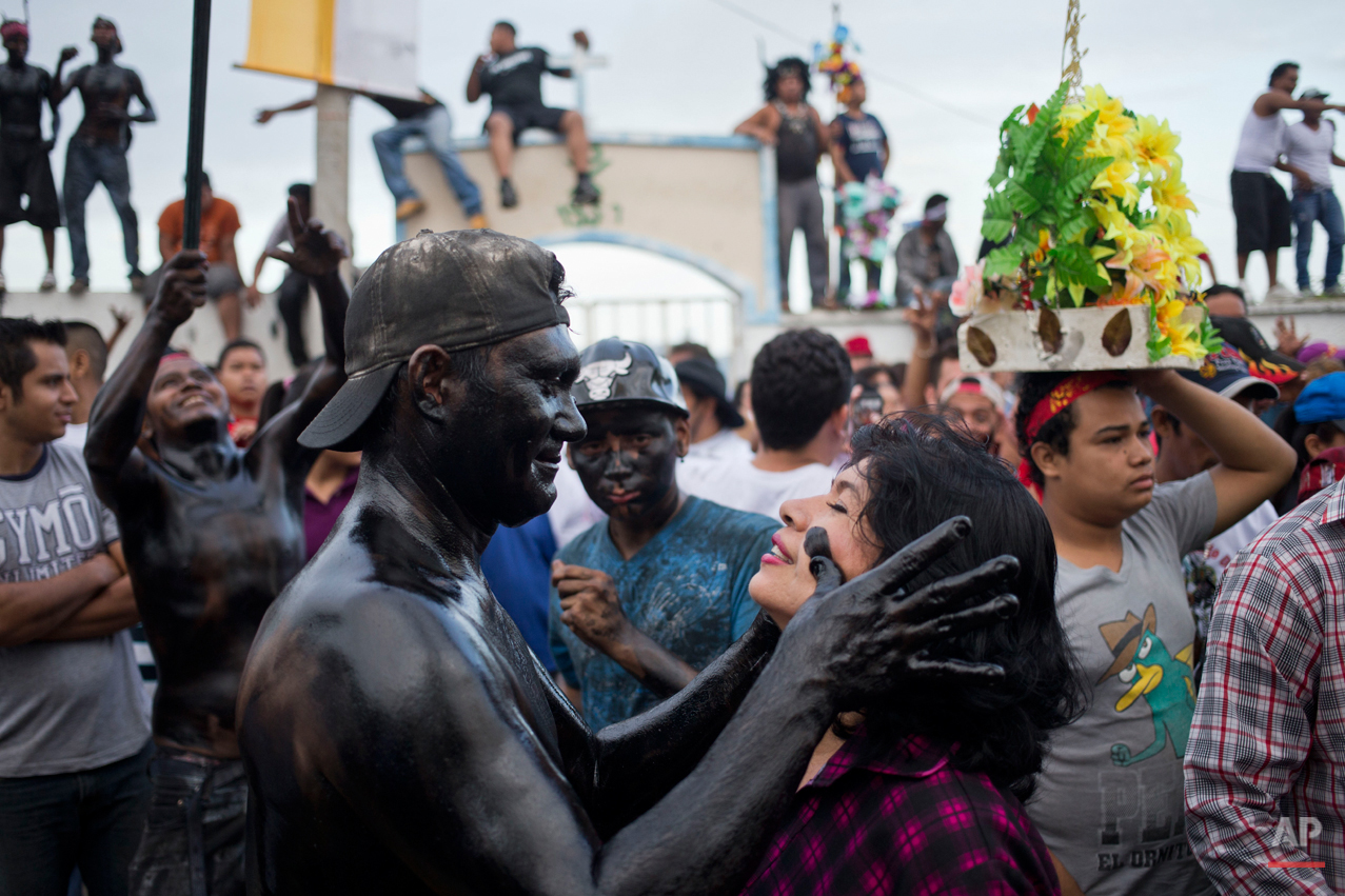  In this July. 31, 2015 photo, a devotee smears a woman's face with black recycled motor oil, during the celebration of the feast of Managua's patron saint, Santo Domingo de Guzman, in Managua, Nicaragua. Covered in motor oil revelers and devotees da