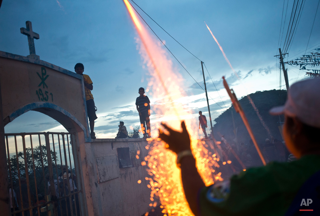  In this Aug. 10, 2015, photo, a fireworks vendor launches a rocket during Managua's patron saint, Santo Domingo de Guzman's celebration, in Managua, Nicaragua. Vendors hawk all kinds of religious items, carnival food, games of chance, toys and popul