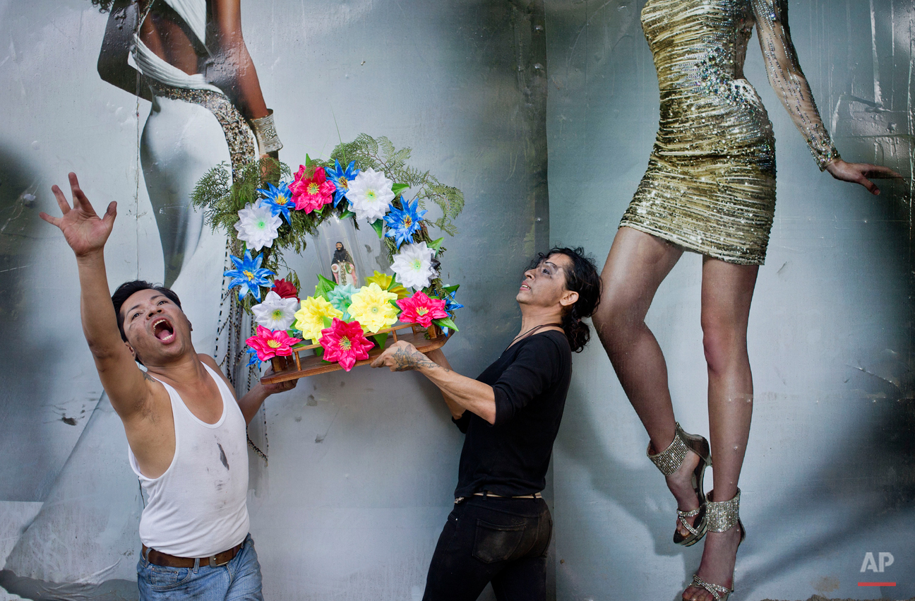  In this Aug. 1, 2015 photo, two men pose for a picture while holding an image of Managua's patron saint, Santo Domingo de Guzman, in front a publicity banner, during the celebration of the saint's feast, in Managua, Nicaragua. The feast is also tied