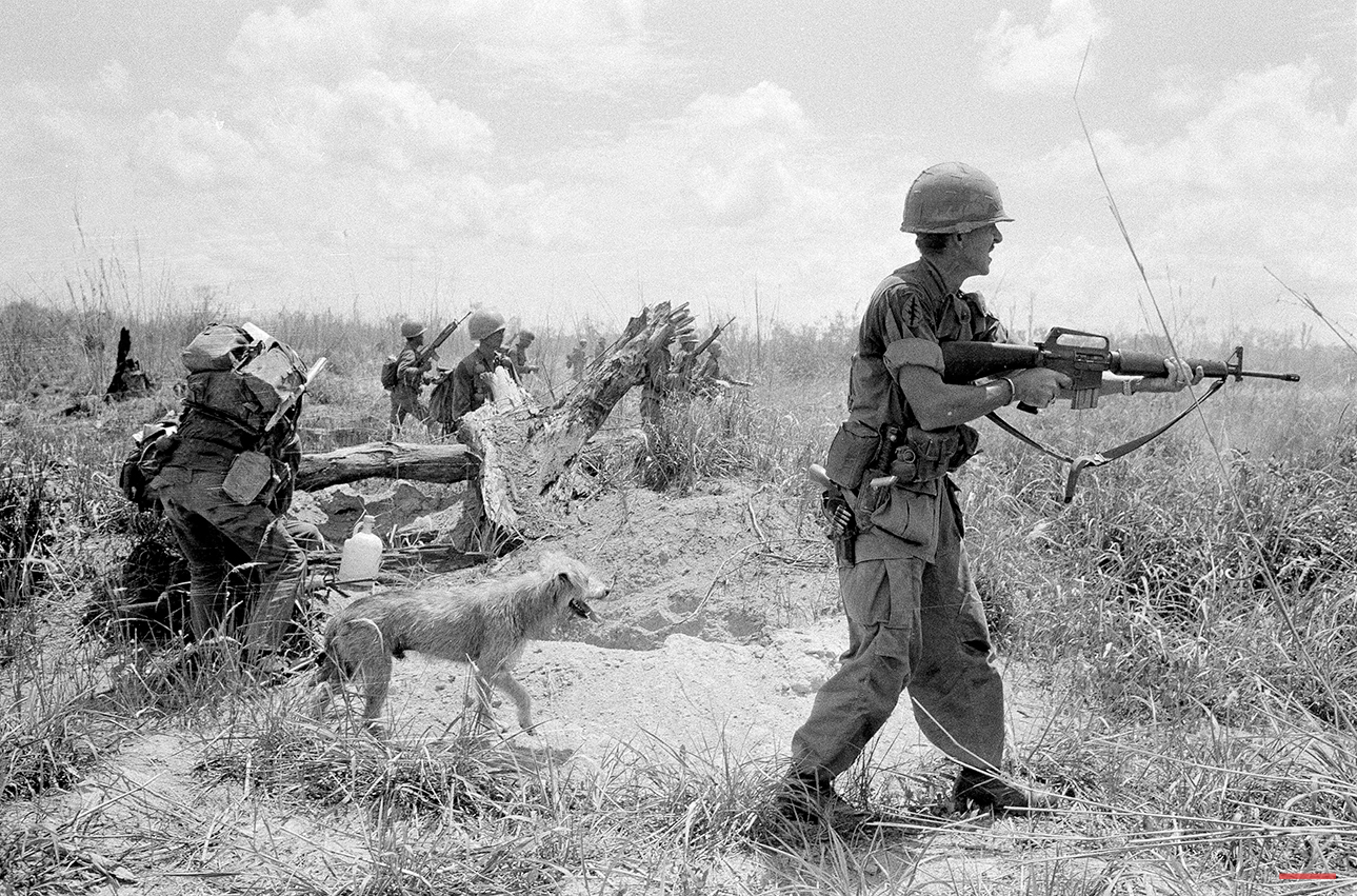 U.S. Adviser Lt. Col. Burr M. Willey, of Ayer, Mass., fired his rifle as he moved up Route 13 with a South Vietnamese army unit toward An Loc, besieged provincial capital north of Saigon. In this scene in Vietnam, May 19, 1972, Willey was followed by his faithful dog Moose and South Vietnamese troops. On June 19, the colonel and his dog were killed during a rocket attack in the area along Route 13. (AP Photo/Nick Ut)