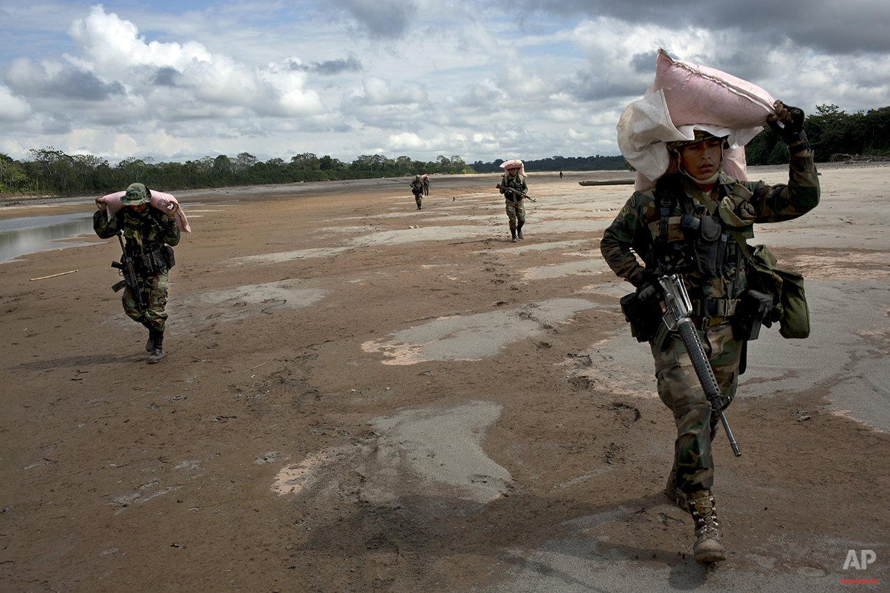  In this July 28, 2015 photo, counternarcotics special forces officers carry sacks of ammonium nitrate explosives to crater a clandestine airstrip in the Peruvian jungle, on the shores of the Palcazu River, near Ciudad Constitucion, Peru. Police say 