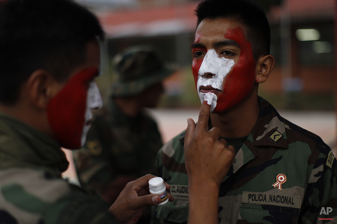  In this July 27, 2015 photo, a counter narcotics police officer paints the face of a comrade before taking part in a parade commemorating Peru's Independence Day, inside their base in Tingo Maria, Peru. The men are part of the elite counternarcotics