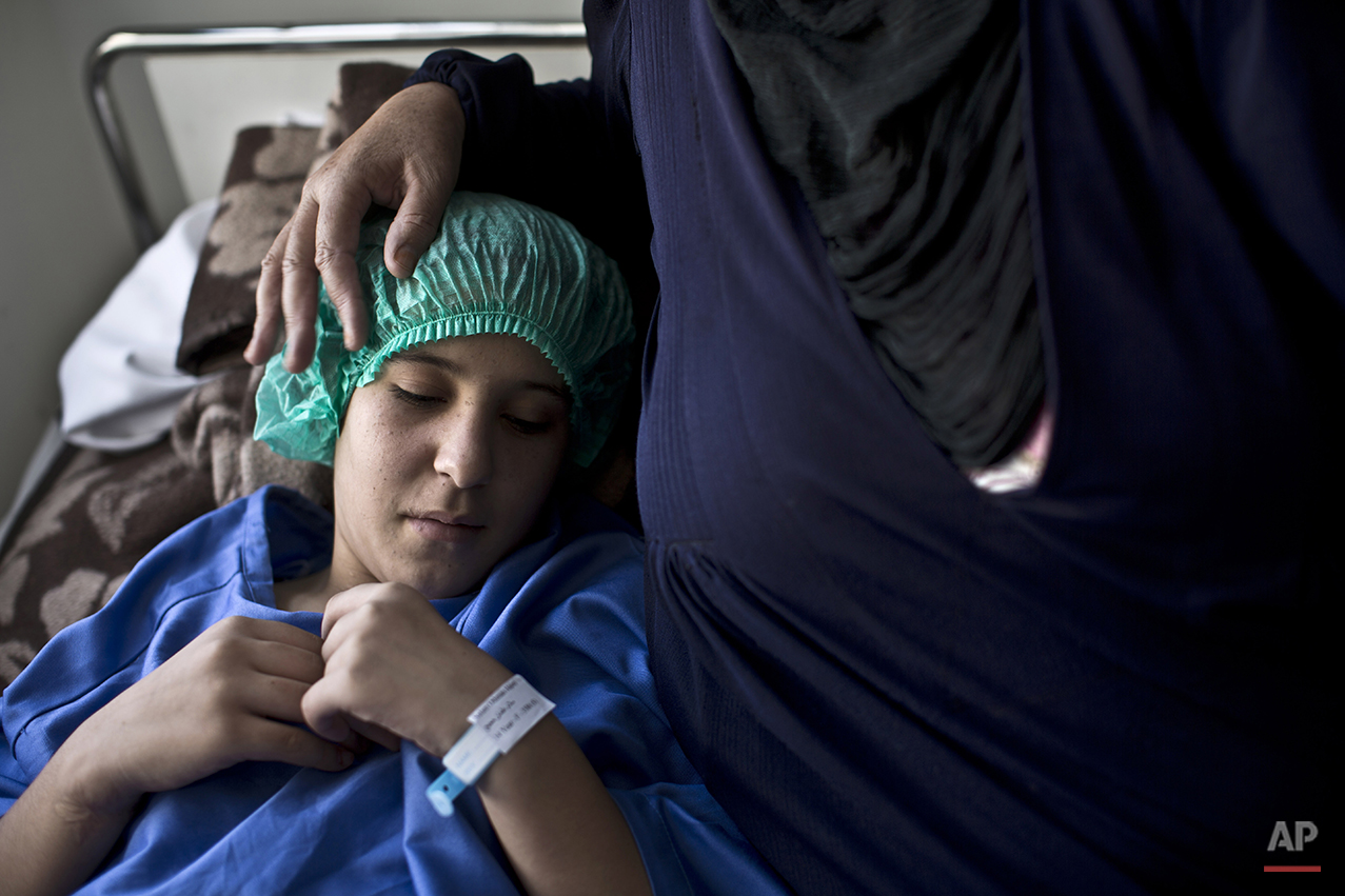  In this Monday, Aug. 17, 2015 photo, Syrian girl Salam Rashid, 14, who lost both of her legs below the knees, is comforted by her mother shortly before a surgery to reshape her stumps for prostheses at MSF Hospital for Specialized Reconstructive Sur