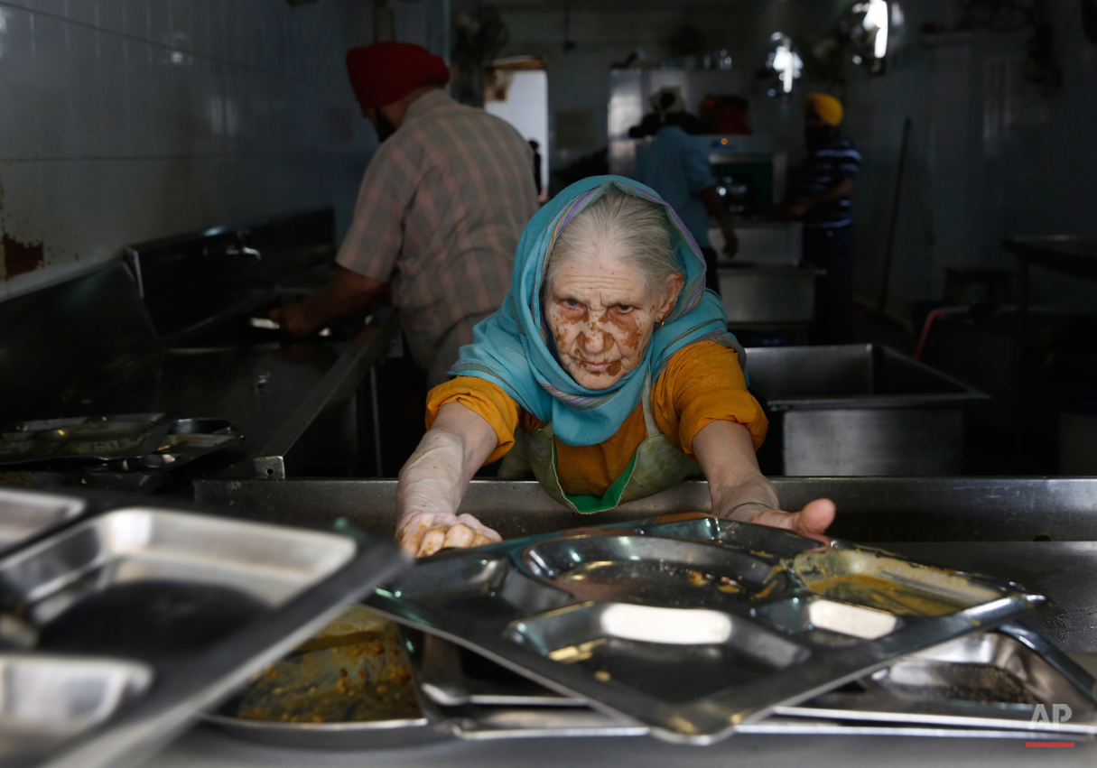  In this May 12, 2015, photo, Paro, uses first name only, collects used plates from devotees for cleaning after they finish langar, which translates to community dinner, at the Bangla Sahib Gurdwara or Sikh temple, in New Delhi, India. Service is one