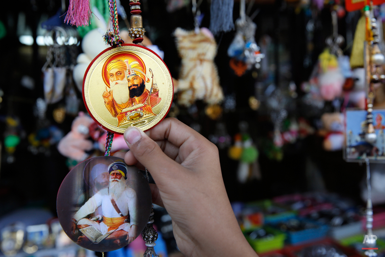  In this June 3, 2015 photo, a devotee holds a badge with portraits of Guru Nanak, left, who founded Sikhism in late 15th century, and Guru Gobind Singh, after eating langar, which translates to community dinner, at Bangla Sahib Gurudwara or Sikh tem