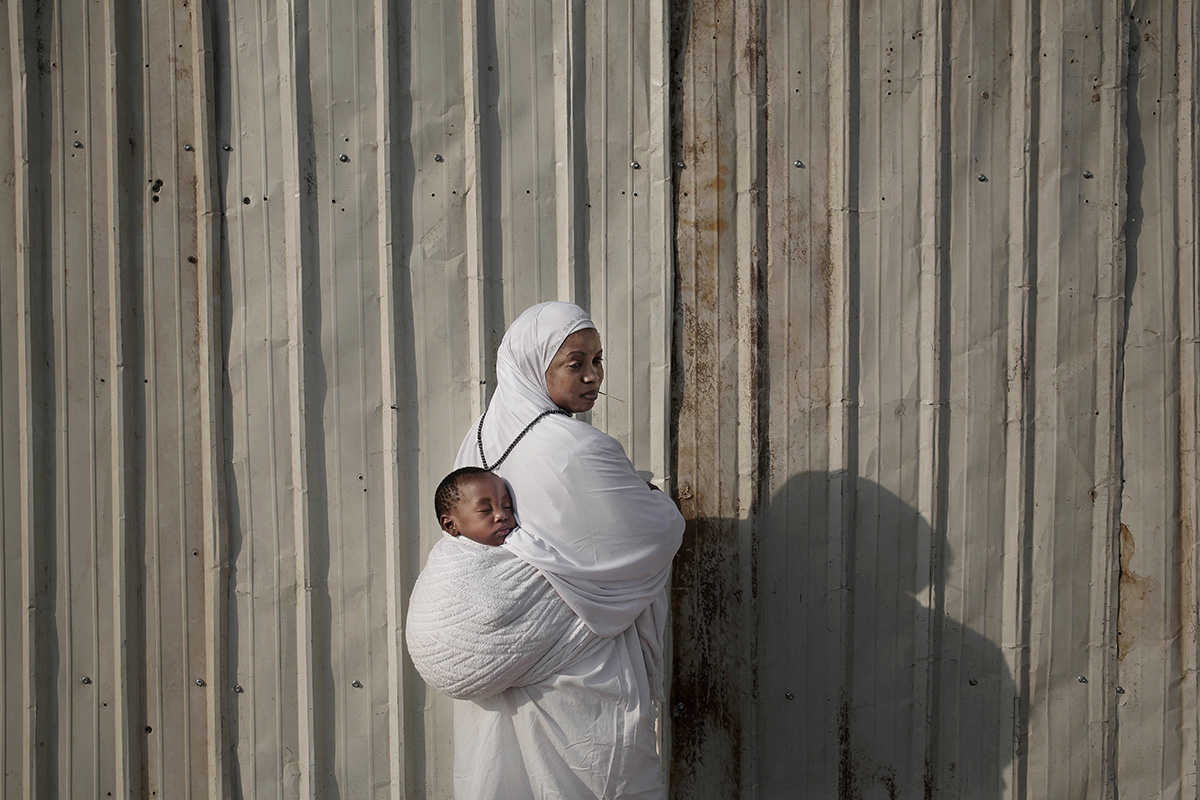 In this Sunday, Sept. 11, 2016 photo, Fatma, 25, from Ghana carries her son Hisou as she poses for a photograph in Arafat during the annual hajj pilgrimage, near the holy city of Mecca, Saudi Arabia. Fatma walked with her son from Madina to Mecca to Arafat and will complete her pilgrimage by walking and not using any vehicles. (AP Photo/Nariman El-Mofty)