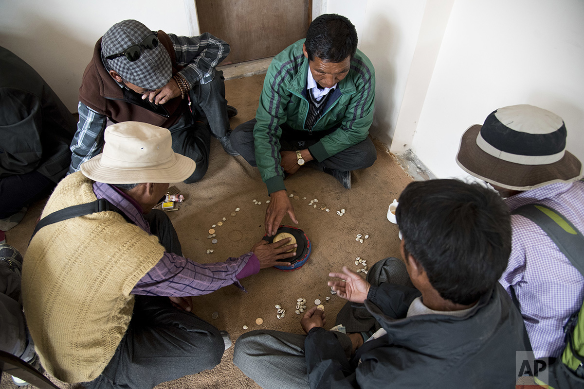  In this Aug. 20, 2016 photo, elders play 'chollo', a game where they shout as they throw the dice to bring good luck, in the city of Kaza, Spiti Valley, India. (AP Photo/Thomas Cytrynowicz) 