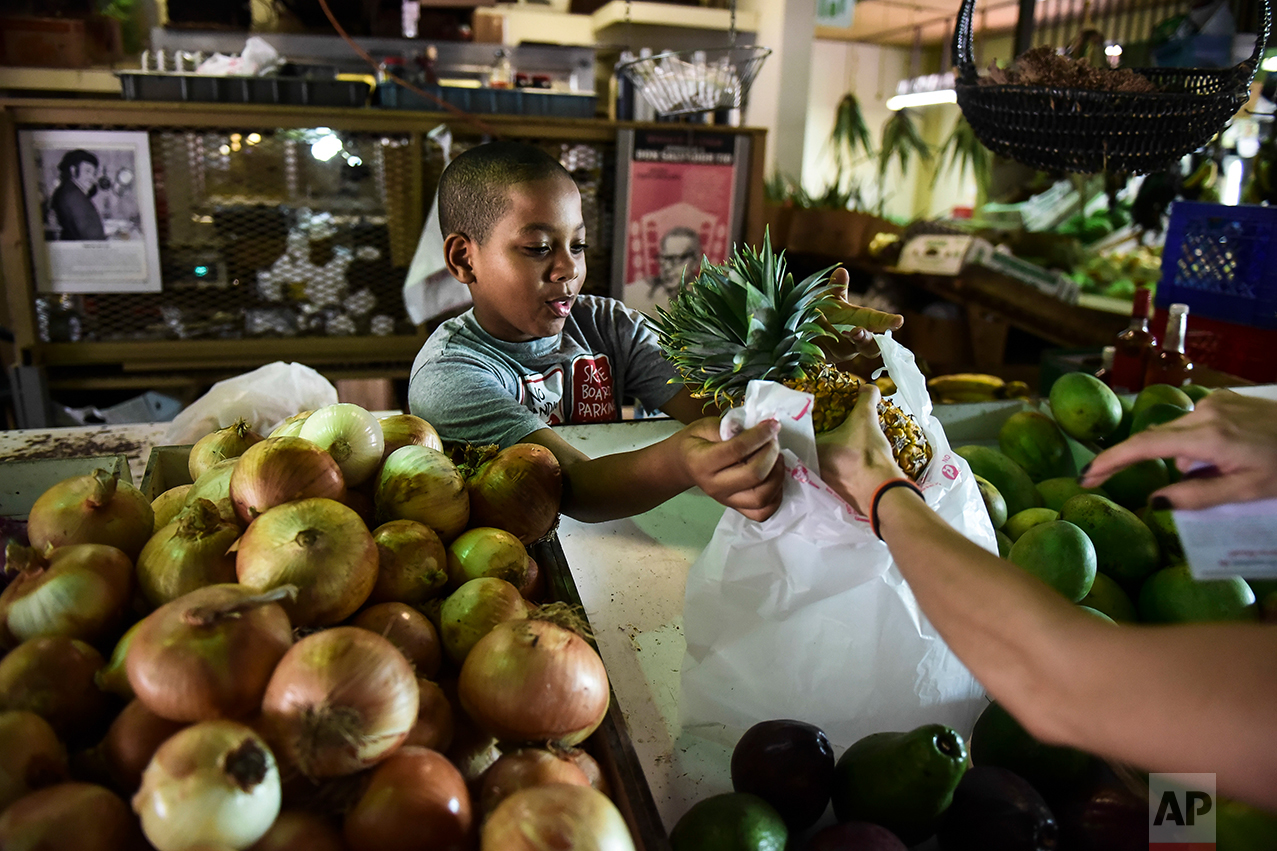  In this Sept. 23, 2016 photo, Yoniel Santana works at his grandmother's produce stand at La Placita de Santurce farmers' market which sells mostly locally grown produce in San Juan, Puerto Rico.&nbsp; (AP Photo/Carlos Giusti) 