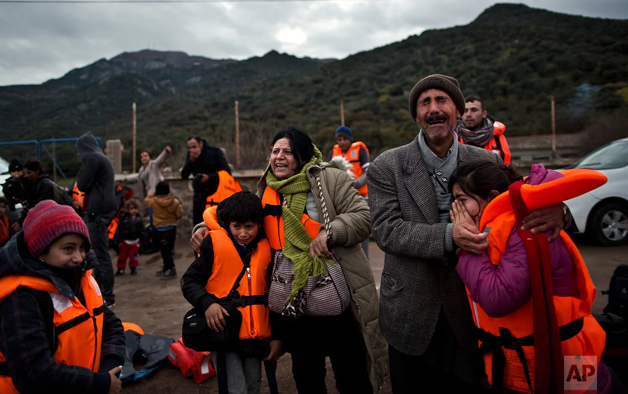 In this Thursday, Dec. 3, 2015 photo, Yazidi refugee Samir Qasu, 45, right, from Sinjar, Iraq, and his wife Bessi, 42, cry while embracing their children, Dunia, 13, and Dildar, 10, shortly after arriving on a vessel from the Turkish coast to the northeastern Greek island of Lesbos. (AP Photo/Muhammed Muheisen)
