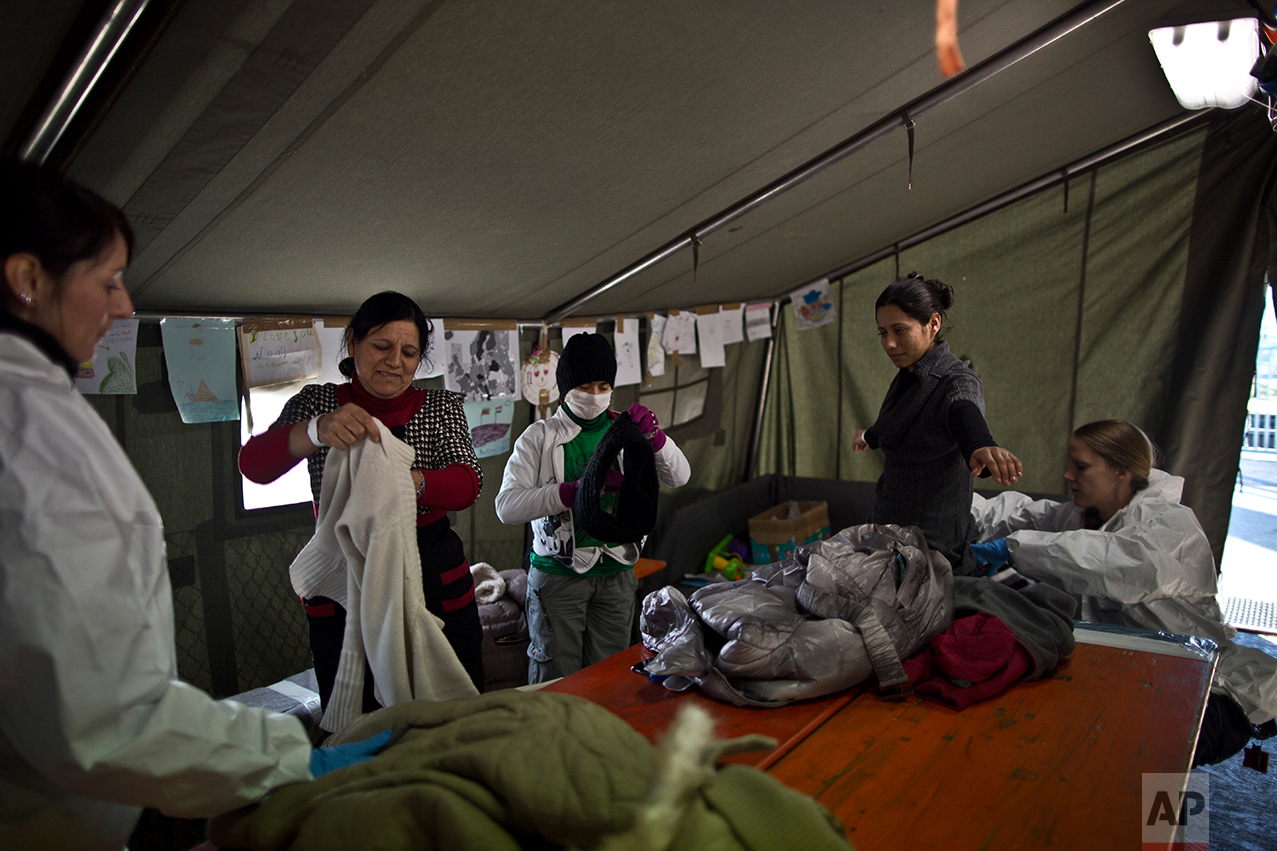  In this Tuesday, Dec. 8, 2015 photo,  Delphine Qasu, 18, a Yazidi refugee from Sinjar, Iraq, right, is body searched by a German police officer next to her sister Dunia, 13, and her mother Bessi, 42, shortly after crossing from Austria to Germany, i