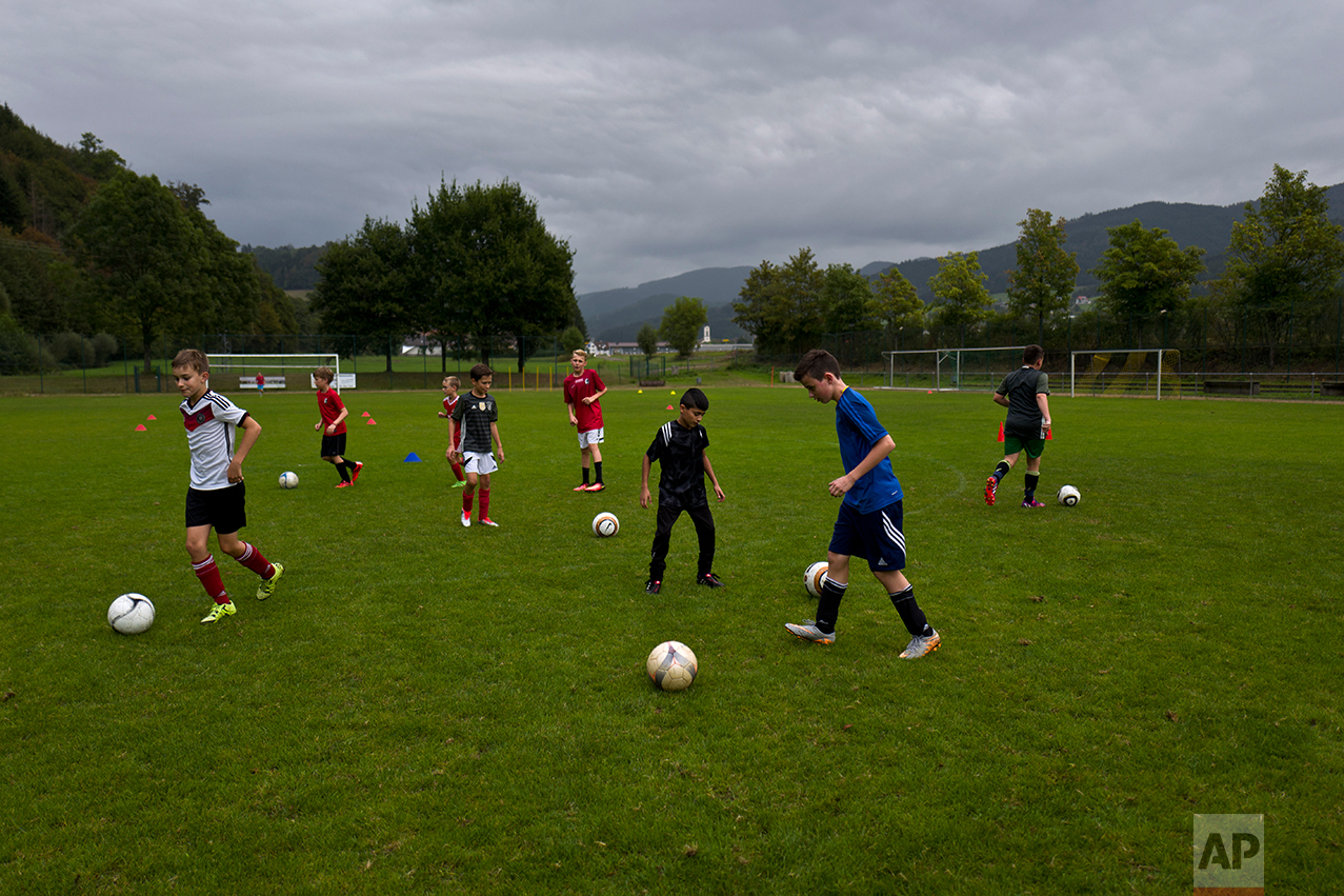  In this Thursday, Sept. 15, 2016 photo, Dildar Qasu, 11, center wearing black, a Yazidi migrant from Sinjar, Iraq, tackles the ball, during a training for the local youth soccer team in Niederwinden, Germany. (AP Photo/Muhammed Muheisen) 