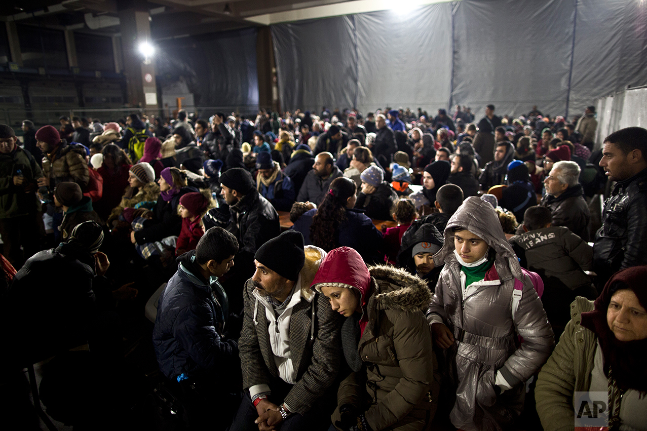  In this Tuesday, Dec. 8, 2015 photo,  Delphine Qasu, 18, a Yazidi refugee from Sinjar, Iraq, rests her head on her father's shoulder after she and the rest of the family arrived on a train coming from Freilassing, at a resting point in Mannheim, Ger