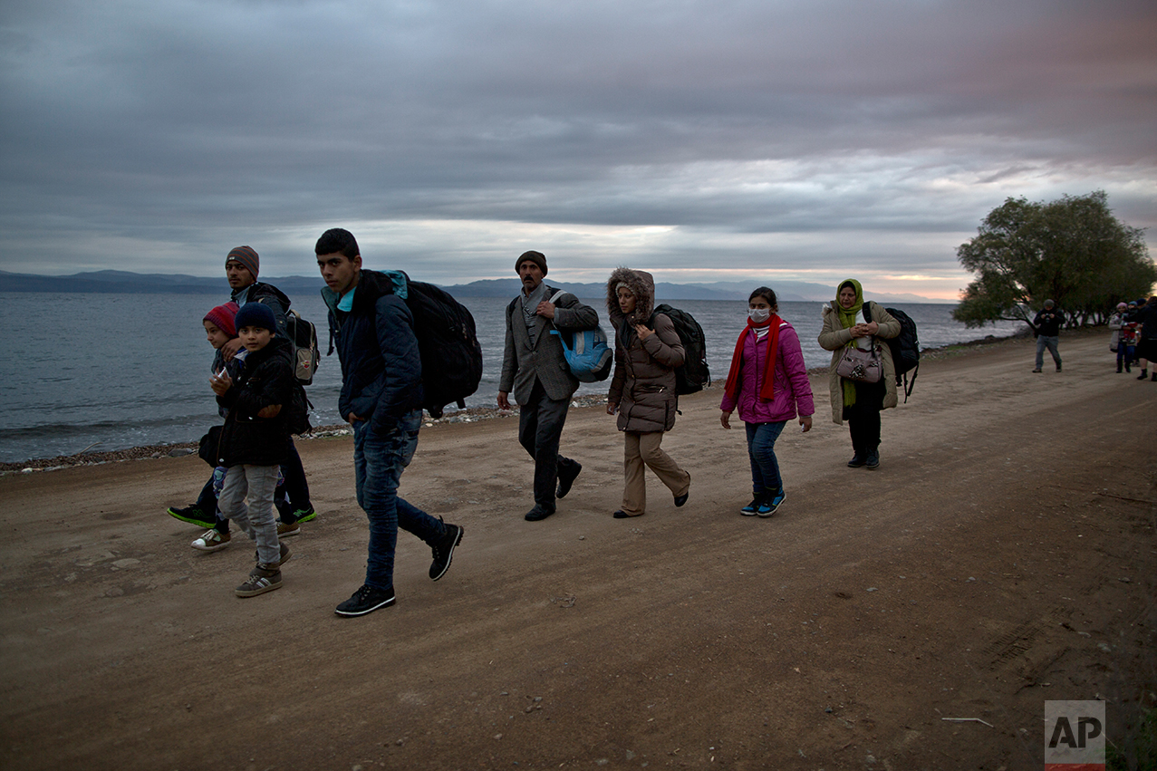  In this Thursday, Dec. 3, 2015 photo, Yazidi refugee Samir Qasu, 45, from Sinjar, Iraq, and his wife Bessi, 42, their two daughters Delphine, 18, Dunia 13, and their two sons Dilshad, 17, and Dildar, 10, walk toward a gathering point to board a bus 