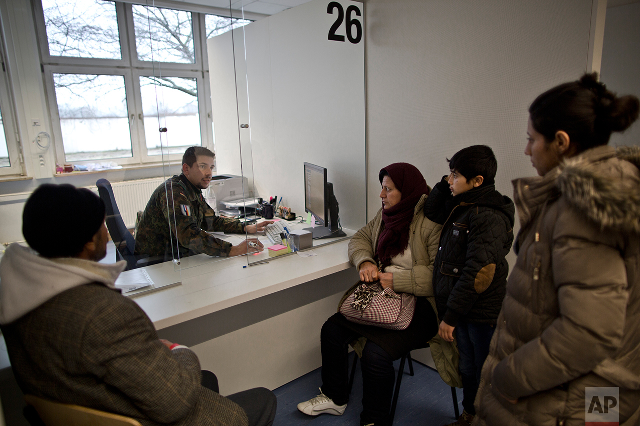  In this Wednesday, Dec. 9, 2015 photo, a German army soldier fills in the details of Qasu family, a Yazidi refugee family from Sinjar, Iraq, as part of their asylum seeking process at the Central Registration Centre in Patrick Henry Village in Heide