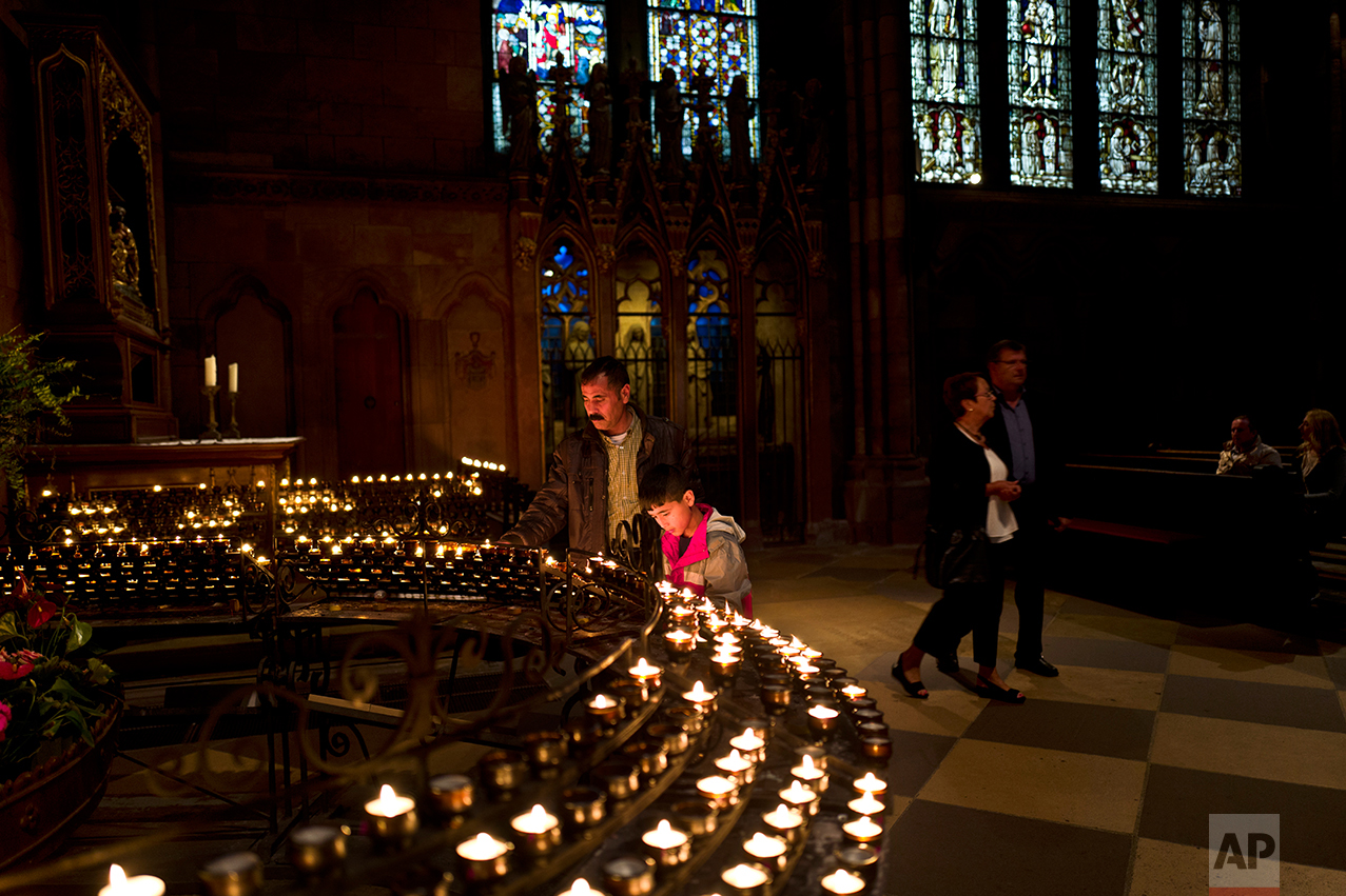  In this Friday, Sept. 16, 2016 photo, Samir Qasu, 46, and his son Dildar, 11, light candles while visiting Freiburg Minster in Freiburg, Germany. (AP Photo/Muhammed Muheisen) 