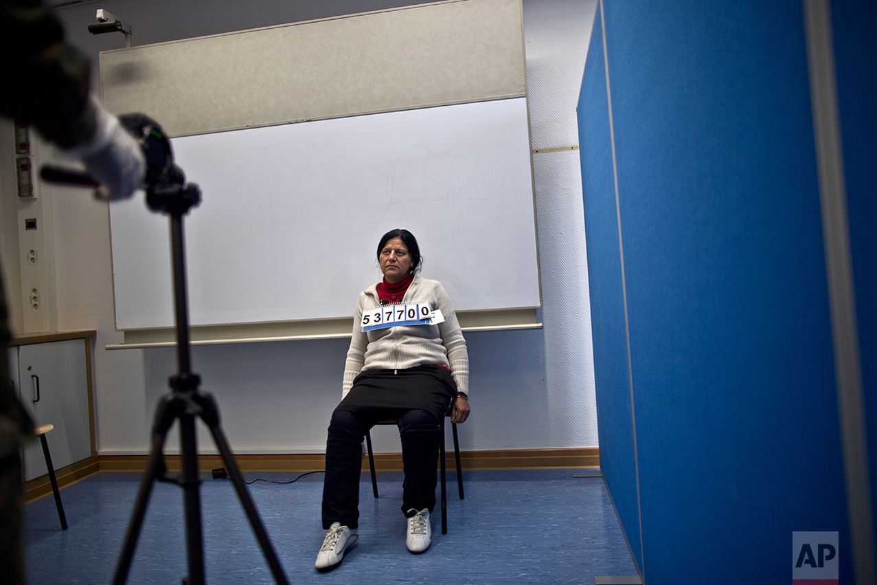  In this Wednesday, Dec. 9, 2015 photo, a German army officer takes a head shot of Bessi Qasim, 42, a Yazidi refugee from Sinjar, Iraq, as part of her asylum seeking process, at the Central Registration Centre in Patrick Henry Village in Heidelberg, 