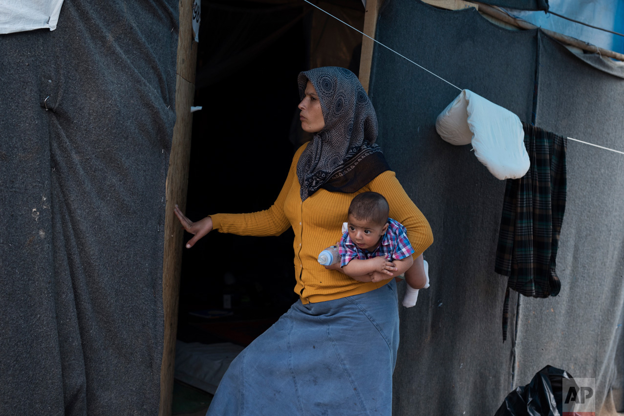  In this Monday, Sept. 19, 2016 photo 30-year-old Rima Al Basir, a Syrian mother from Alepo, enters her makeshift tent carrying her five-month-old baby boy Mohamed Ahmed Bashar at the Ritsona camp north of Athens. Her baby is one of at least seven bo