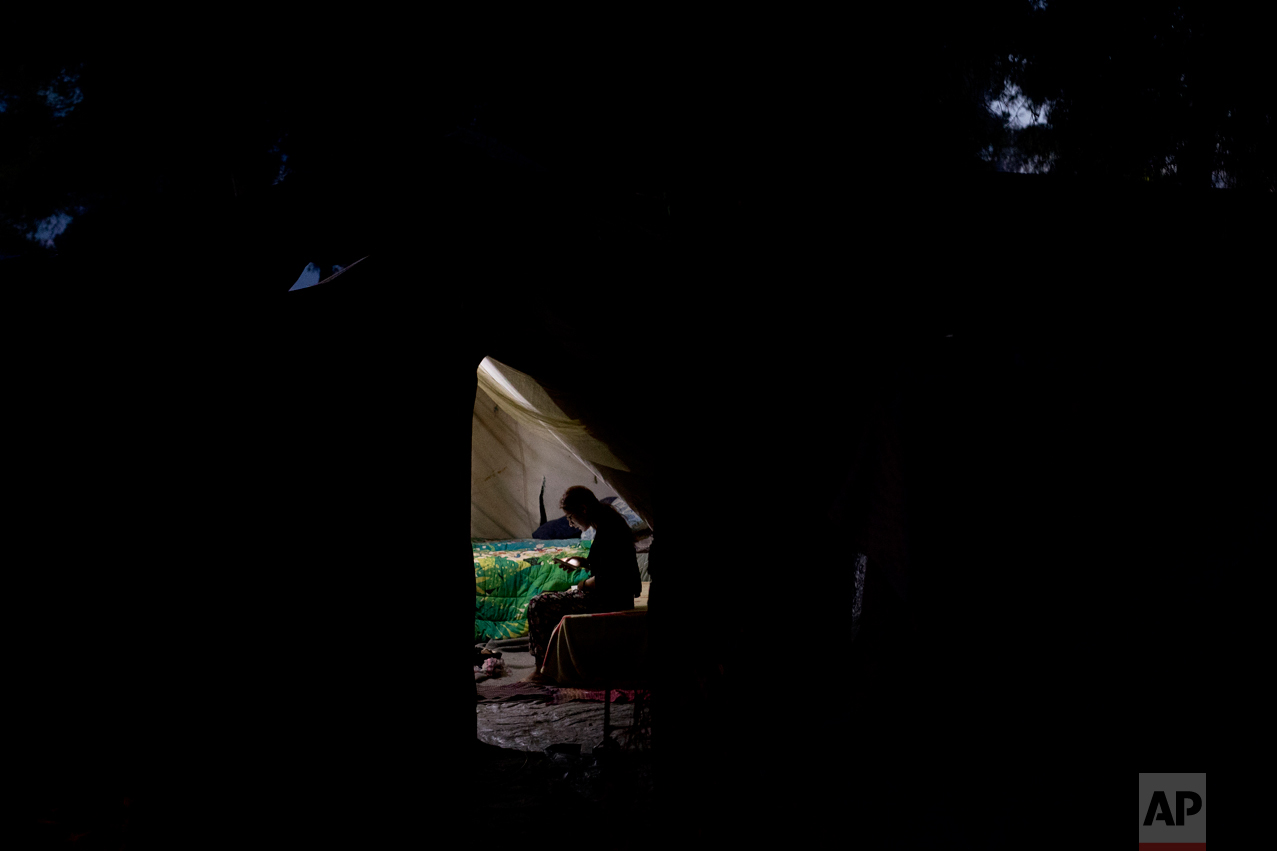  In this Monday, Sept. 12, 2016 photo, a Syrian woman uses her mobile phone inside a tent at the Ritsona camp for refugees and other migrants north of Athens. Residents have access to free wifi services, and keep up to date on developments in their h