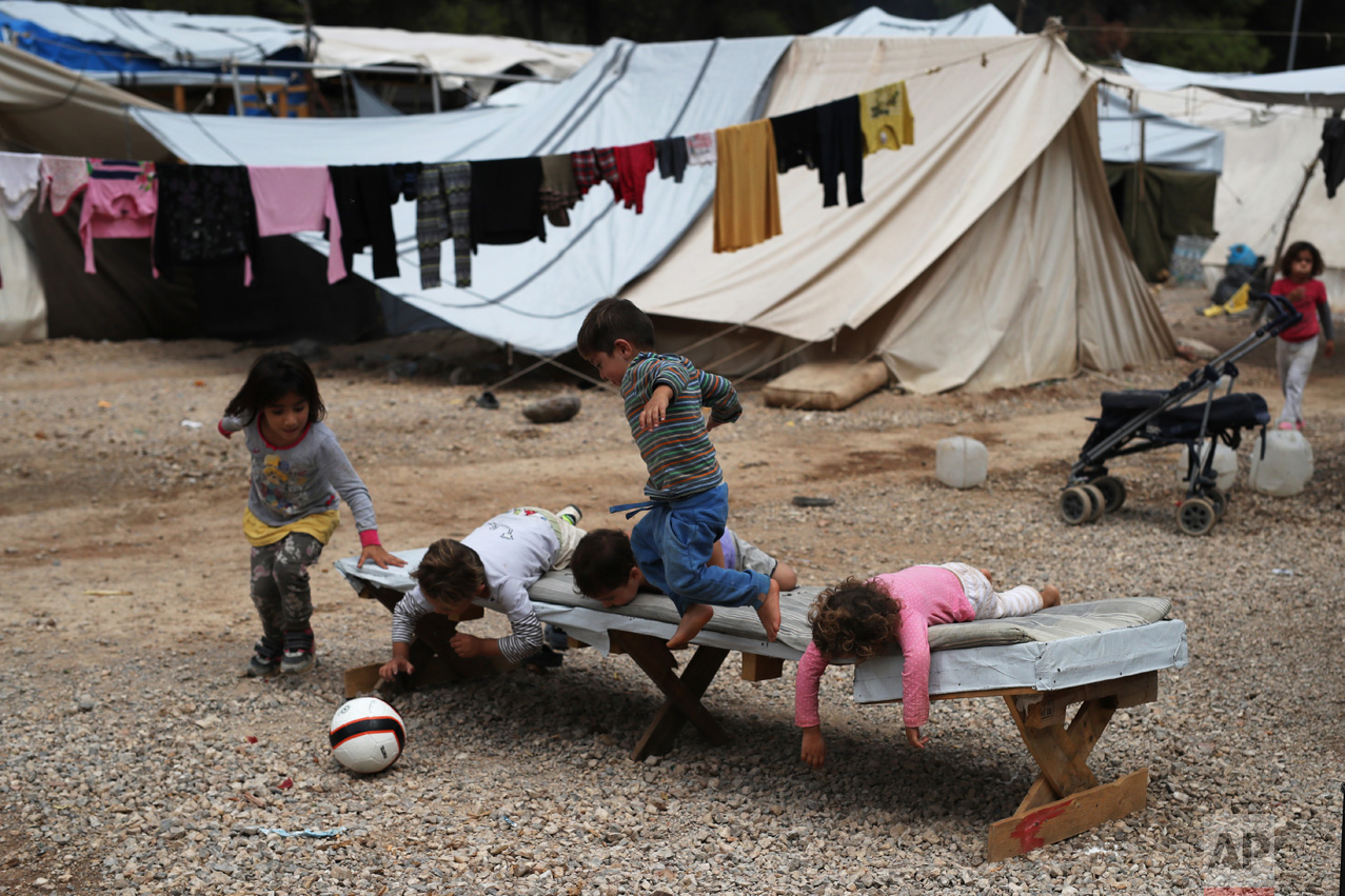  In this Monday, Sept. 19, 2016 photo, Syrian refugee children play on a trestle bed, as a line of washing hangs from tents behind them, at the Ritsona camp for refugees and other migrants north of Athens. (AP Photo/Petros Giannakouris) 