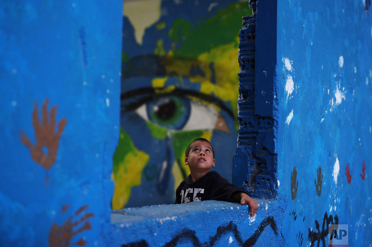  In this Tuesday, Sept. 13, 2016 photo, a Syrian child plays in front of graffiti at the Ritsona camp for refugees and other migrants north of Athens. About 600 people _ including 160 children _ live in the camp. (AP Photo/Petros Giannakouris) 