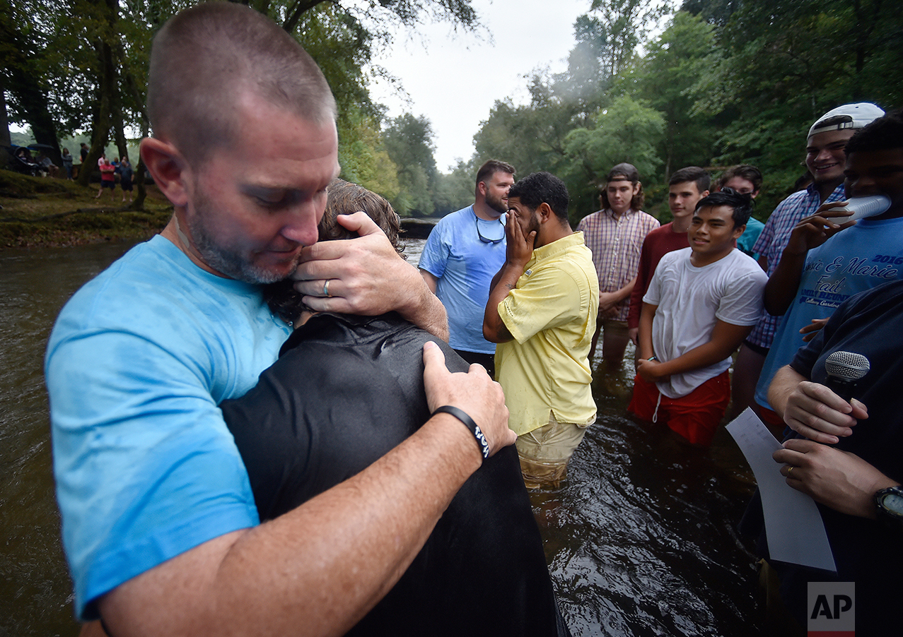  Habersham Central High School student and football player Garrett Kinsey is hugged by Head Football coach Benji Harrison, left, as Marvin Alford reacts, center, after Kinsey was baptized in the Chattahoochee River, Sunday, Sept. 18, 2016, near Demor
