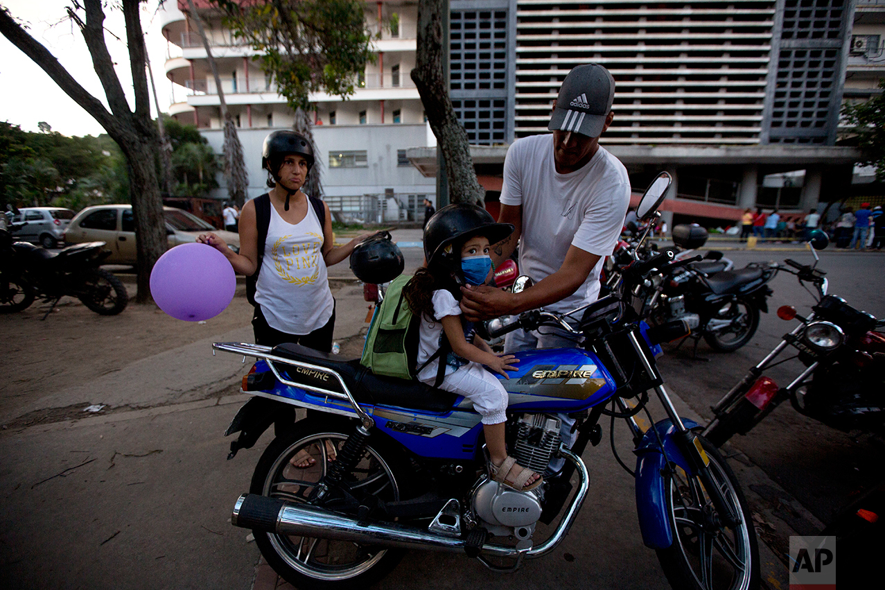In this Sept. 19, 2016 photo, Maykol Pacheco, places a helmet on his daughter Ashley as they prepare to ride away from the University Hospital in Caracas, Venezuela. Two weeks after 3-year-old Ashley scraped her knee, she was screaming in a hospital, fighting for her life as her family scoured Caracas for scarce antibiotics. Venezuela is running short on 85 percent of basic medicines. As the health care system collapses, the tiniest slips, like a little girl’s tumble while chasing her brother, are turning into life-or-death crises. (AP Photo/Fernando Llano)