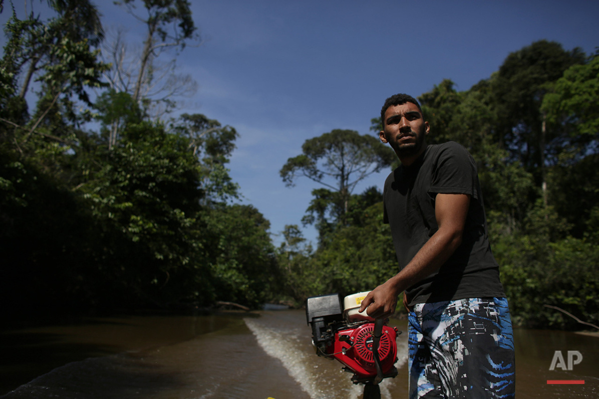 In this June 22, 2016 photo, boatman Sebastiao Melo pilots his boat through the Igarape Mapia river towards the Ceu do Mapia community in Amazonas state, Brazil. This community revolves around an ancient psychedelic tea locals know as the Holy Daime. The Ayahuasca brew is sacred to Ceu do Mapia villagers, who use it in rituals that blend together Indian beliefs with Roman Catholicism. (AP Photo/Eraldo Peres)