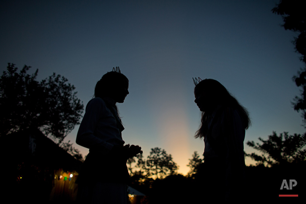  In this June 23, 2016 photo, girls talk at sunrise after an all night religious service of the church of the doctrine of the Holy Daime in Ceu do Mapia, Amazonas state, Brazil. For the service women wear shiny white crowns on their heads, green sash