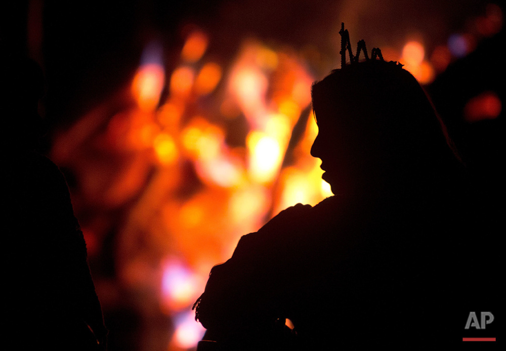  In this June 22, 2016 photo, a woman wearing a white crown warms up next to a bonfire during a break in the service of the church of the doctrine of the Holy Daime, in Ceu do Mapia, Amazonas state, Brazil. During the all night service men and women 