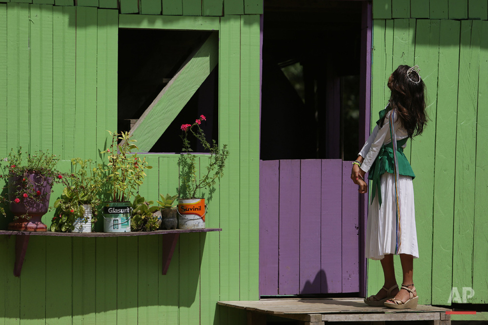  In this June 22, 2016. photo, 12-year-old Maria Clara, preens in front of her house before going to the religious service of Holy Daime in Ceu do Mapia, Amazonas state, Brazil. The whole village gathers to celebrate the Brazilian harvest and the fea