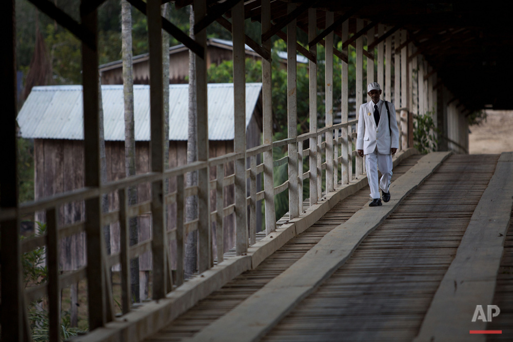  In this June 22, 2016 photo, a man dressed in white walks on the community's main bridge to participate in the Holy Daime ritual in Ceu do Mapia, Amazonas state, Brazil. Men and women gather in the local church to celebrate the Brazilian harvest and