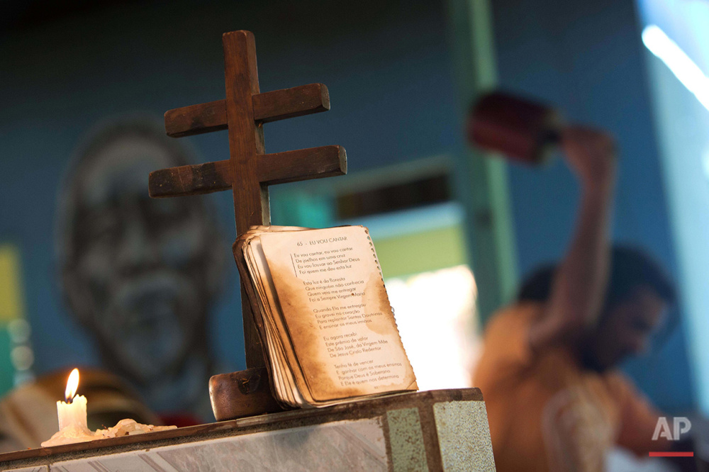  In this June 22, 2016 photo, a man crushes vines to make an ancient psychedelic tea locals know as the Holy Daime, in front of a cross and a book of hymns of the doctrine of Santo Daime, in Ceu do Mapia, Amazonas state, Brazil. Brewing the sacrament