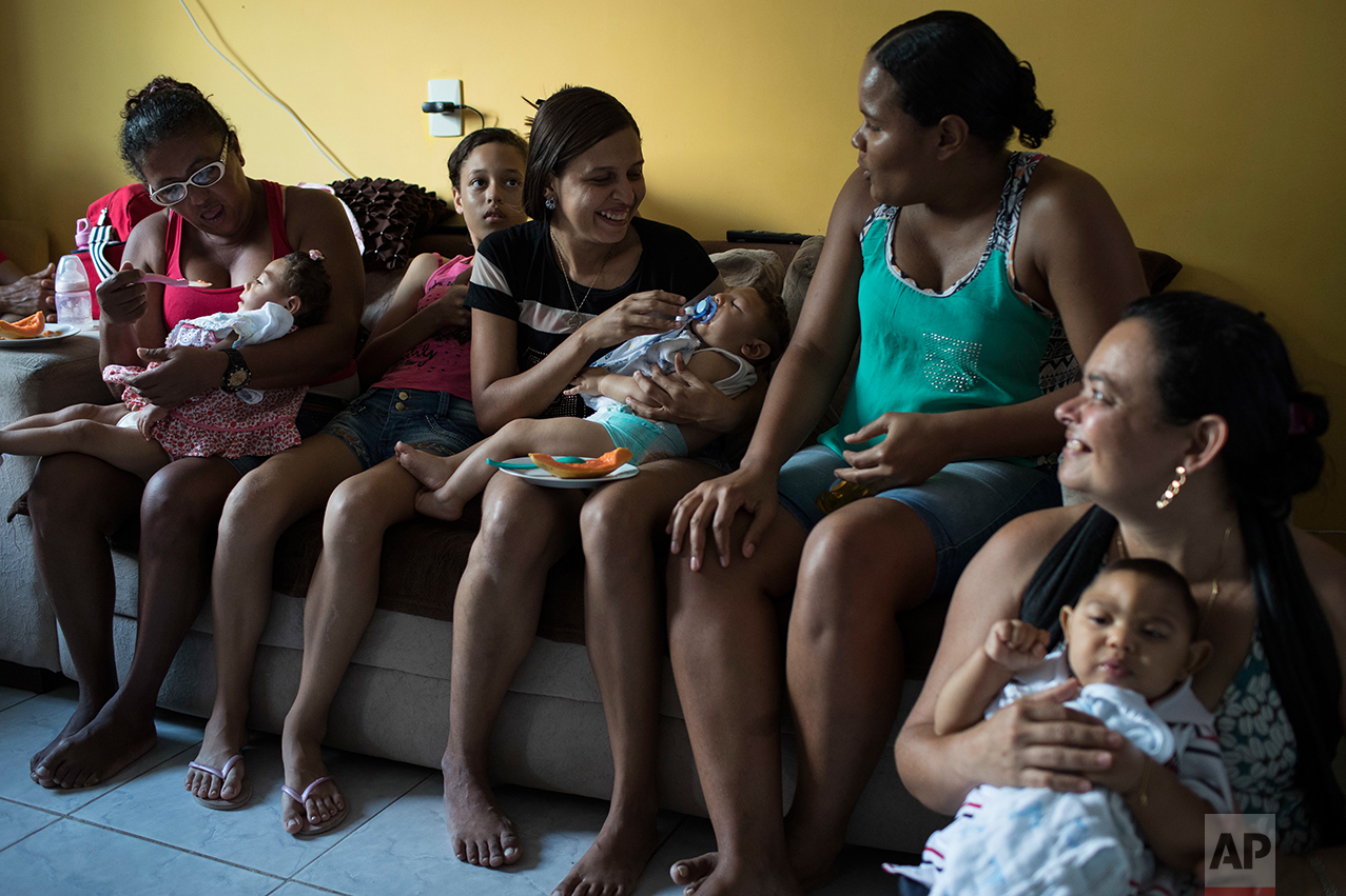 In this Oct. 1, 2016 photo, mothers hold their babies, who have microcephaly, from left, Alice Vitoria, Juan Pedro and Joao Guilherme, during Arthur's one-year birthday party, at his home in Recife, Pernambuco state, Brazil. Away from medical facilities, many of the mothers of babies born with microcephaly get together and try to keep a semblance of normalcy by celebrating milestones, like first birthdays. (AP Photo/Felipe Dana)