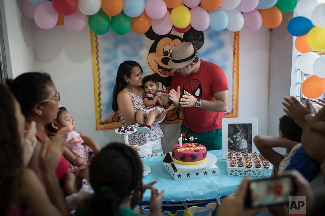 In this Oct. 1, 2016 photo, Rozilene Ferreira and her husband Elias Rodrigo celebrate the one-year birthday of their son Arthur, who was born with microcephaly, in Recife, Pernambuco state, Brazil. Arthur has started taking high-calorie formula through a tube after he appeared to choke during meals. “It’s every mom’s dream to see their child open his mouth and eat well,” said his mother, adding that each day seems to bring new problems. (AP Photo/Felipe Dana)