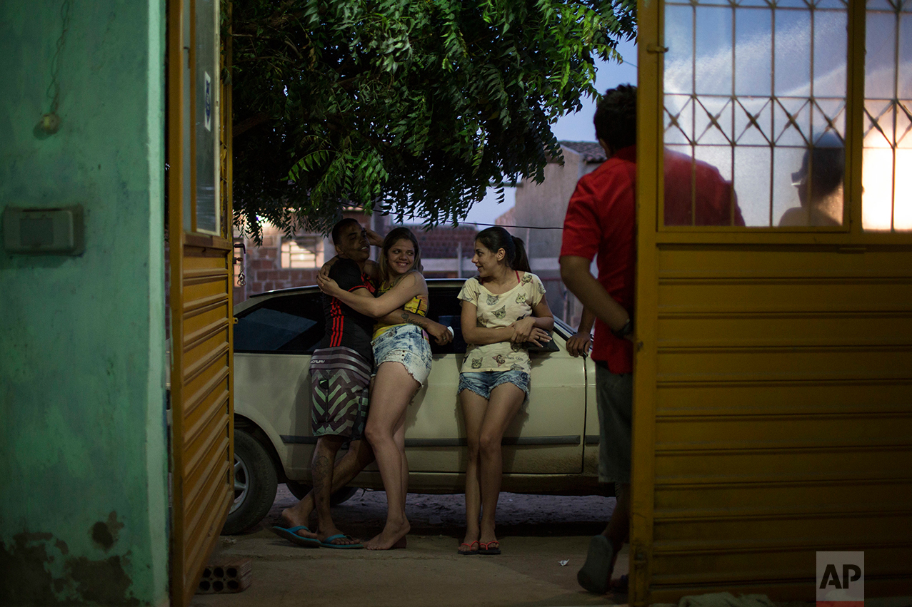 In this Sept. 26, 2016 photo, Angelica Pereira, center right, chats with her sister and sister's boyfriend outside her home as her infant daughter Luiza, who was born with microcephaly, sleeps in Santa Cruz do Capibaribe, Pernambuco state, Brazil. A year after a spike in the number of newborns with the defect known as microcephaly, doctors and researchers have seen many of the babies develop swallowing difficulties, epileptic seizures and vision and hearing problems. (AP Photo/Felipe Dana)