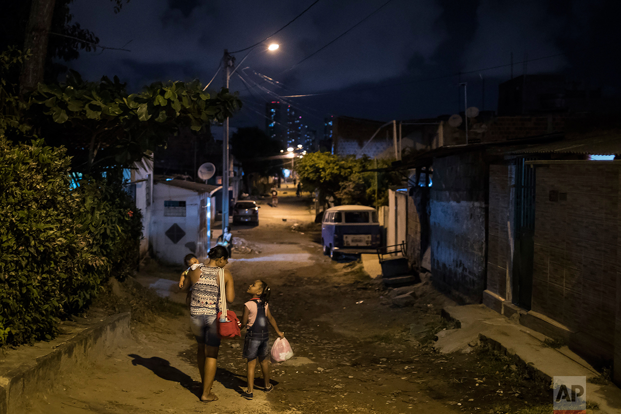 In this Oct. 1, 2016 photo, Vanessa dos Santos holds her son Enzo, who was born with microcephaly, as she walks home with her daughter Lorena in Recife, Pernambuco state, Brazil. Studies are underway to determine if the timing of mothers who were infected with Zika during pregnancy affects the severity of the abnormalities, said Ricardo Ximenes, a researcher at the Fiocruz Institute in Recife. (AP Photo/Felipe Dana)