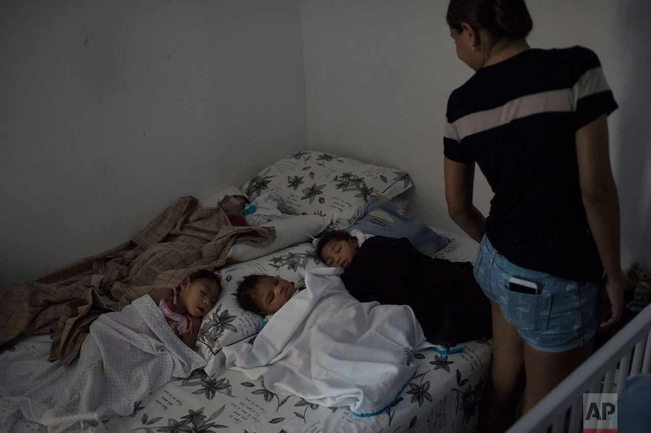 This Oct. 1, 2016 photo shows Daniele Ferreira looks over Arthur Conceicao, counter clockwise beginning from back left, sleeping at his one-year birthday party, next to Alice, Enzo, and Mateus, all born with microcephaly, in Recife, Pernambuco state, Brazil. Away from medical facilities, many of the mothers of babies afflicted with microcephaly, get together and try to keep a semblance of normalcy by celebrating milestones, like first birthdays. (AP Photo/Felipe Dana)