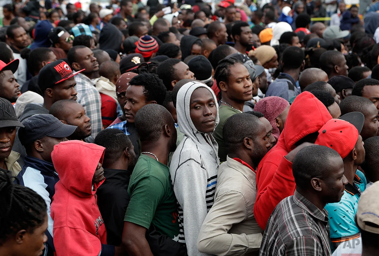 In this Oct. 3, 2016 photo, Haitians line up at an immigration agency in Tijuana, Mexico with the hope of gaining an appointment to cross to the U.S. side of the border. U.S. Customs and Border Protection can only handle up to about 75 people a day at San Ysidro, and Tijuana authorities were unhappy about large crowds assembled on the Mexican side of the border crossing. (AP Photo/Gregory Bull)