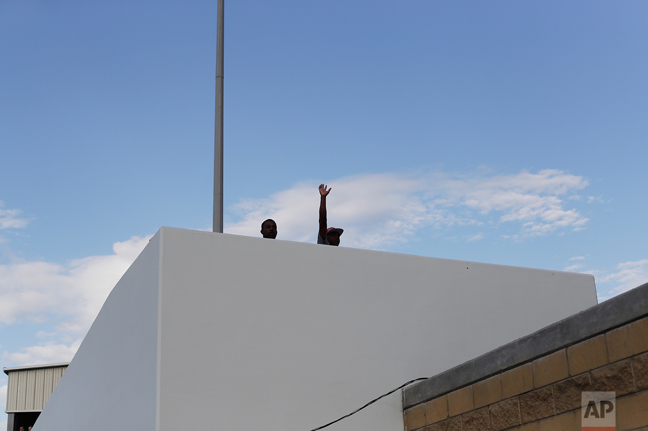 In this Sept. 27, 2016 photo, a Haitian migrant waves on his way to the U.S. border crossing, in Tijuana, Mexico. The U.S. Department of Homeland Security on Sept. 22 halted the humanitarian parole it had given Haitians following a massive 2010 earthquake. Instead of releasing the Haitians into the United States, under a general policy the U.S. is now confining them to a detention facility and it plans to start deporting them back to the homeland they hoped to flee. (AP Photo/Gregory Bull)