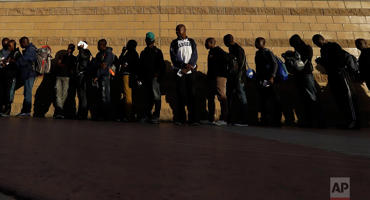 In this Sept. 2, 2016 photo, Haitian migrants line up as they wait to enter the U.S. border crossing, in Tijuana, Mexico. As the U.S. repatriate the migrants it has a limited number of beds at its immigration detention facilities to accommodate people while flights and travel documents are arranged. (AP Photo/Gregory Bull)